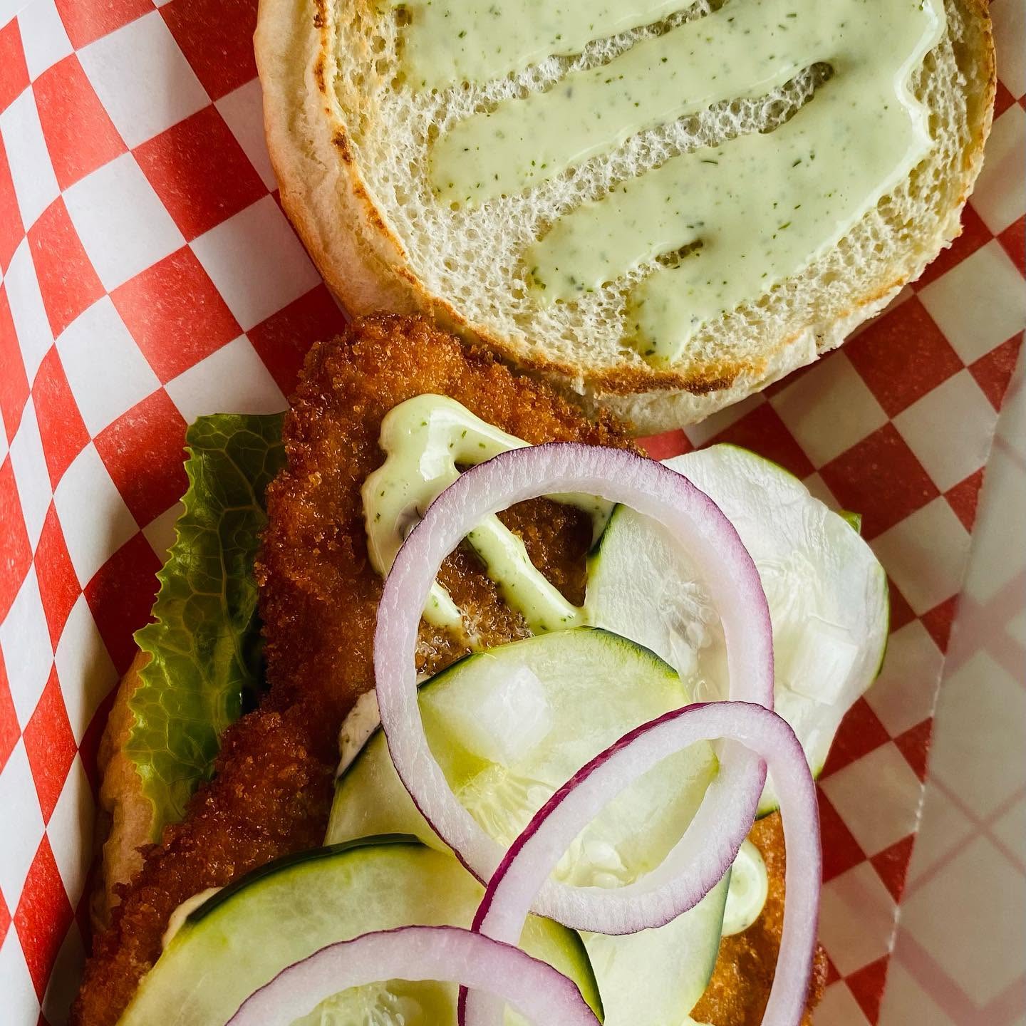 Crispy chicken sandwich with dill sauce, onion and cucumber