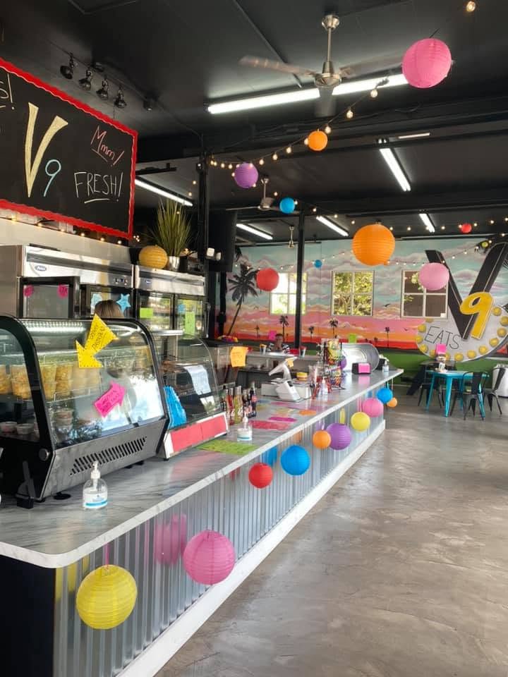 Inside V9 EATS: the long service counter under string lights and paper lanterns