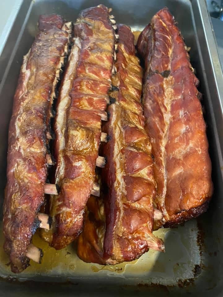 Pan of slow-smoked baby back ribs, glossy with bark