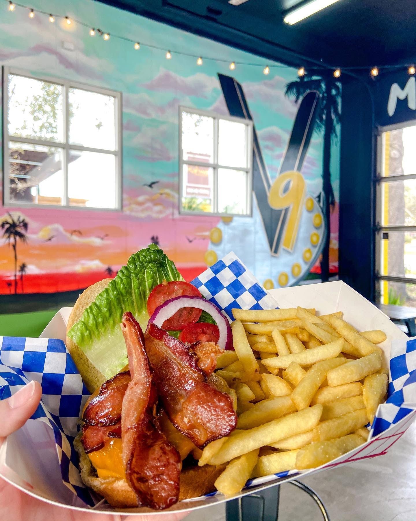 Bacon burger and fries under the painted mural and marquee sign