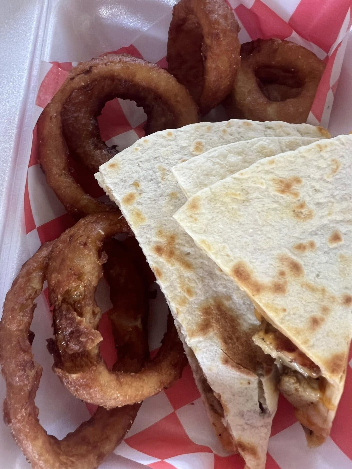Onion rings and a quesadilla in a checkered basket