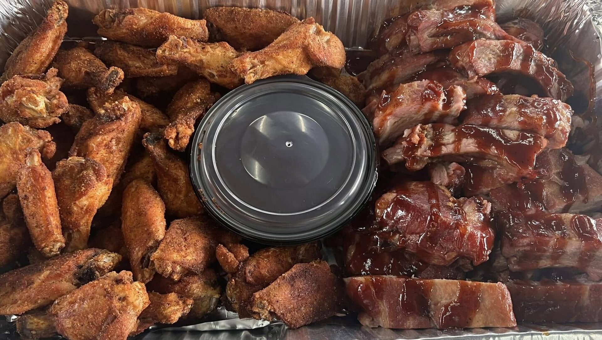 Catering tray of smoked wings and sliced ribs