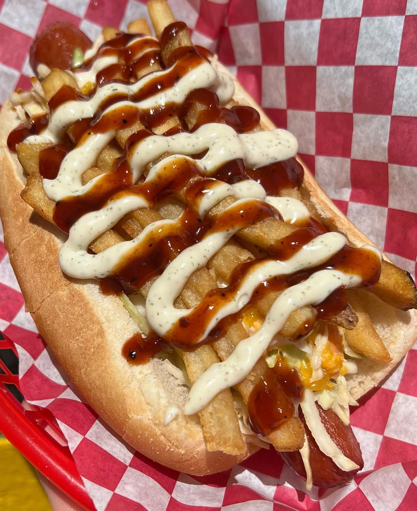 The Saint Pete Dog topped with fries, slaw, spicy BBQ and dill sauce in a red basket