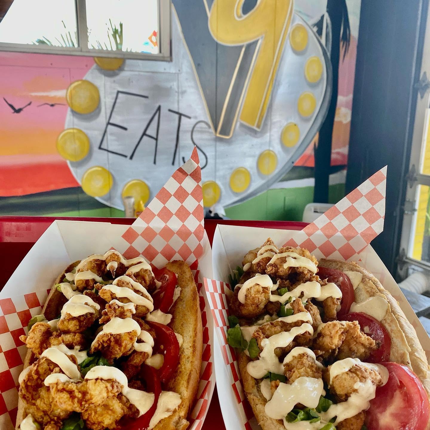 Two loaded hot dogs in checkered boats under the marquee sign