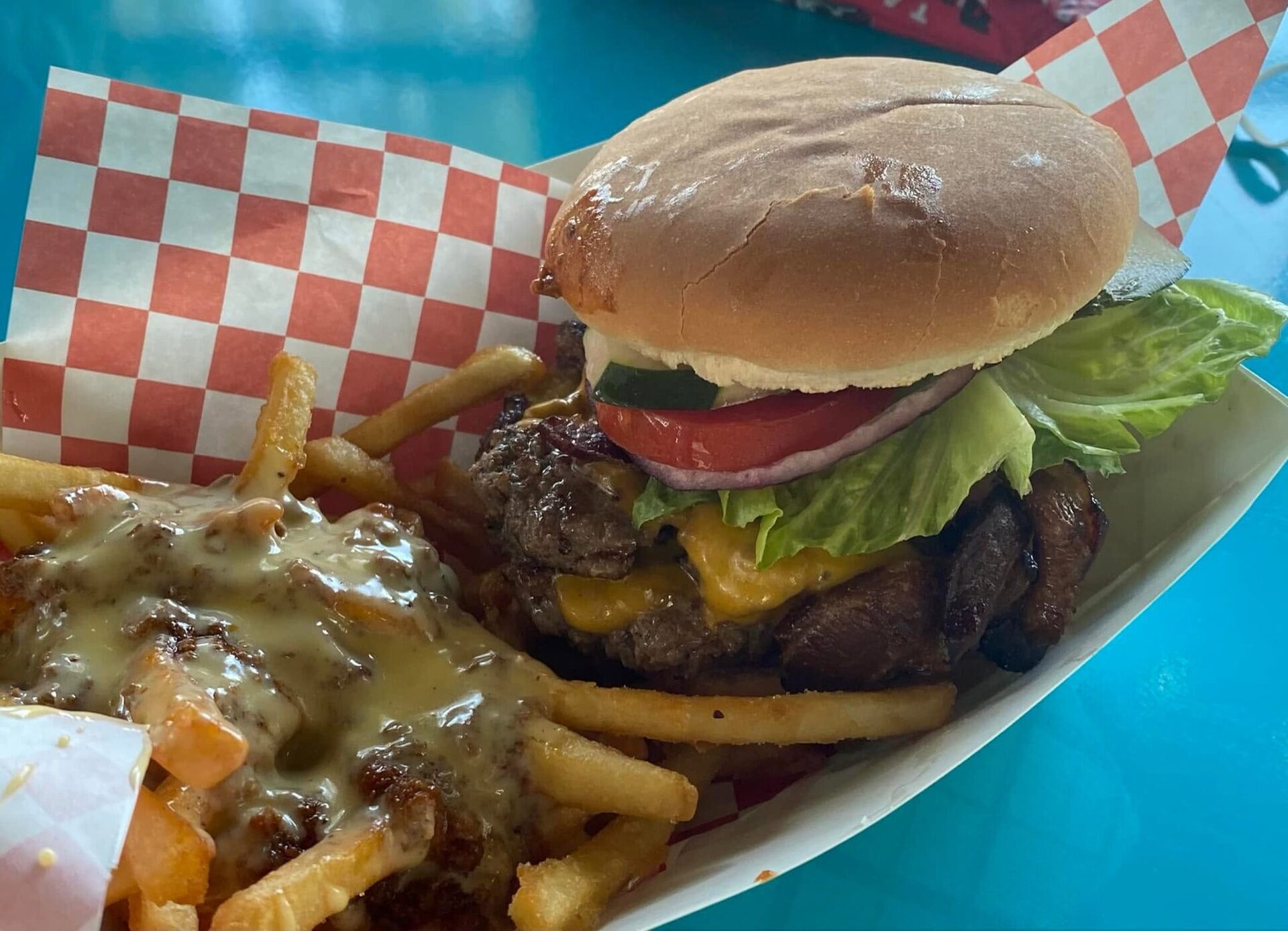 Burger and loaded fries on a teal table