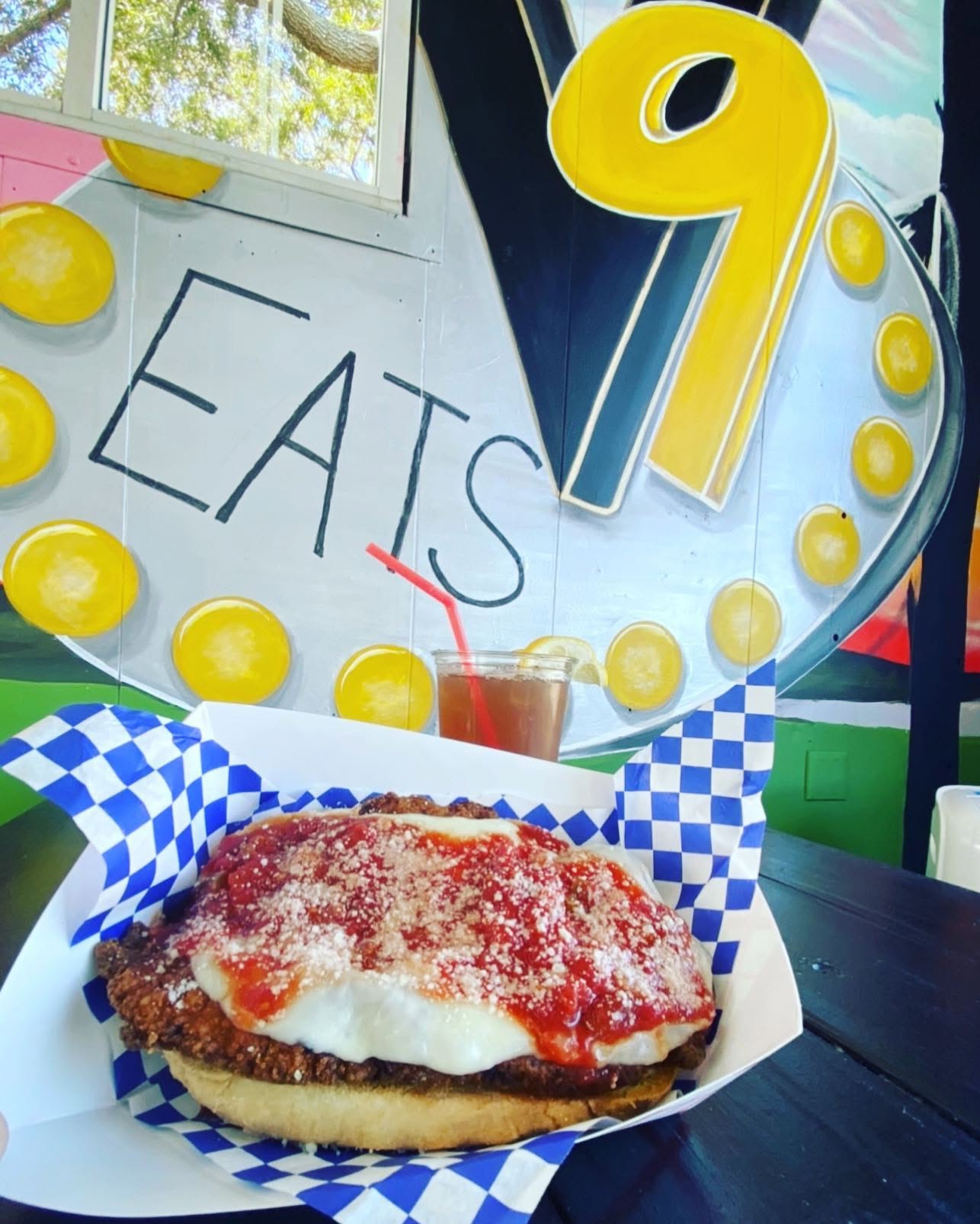 Chicken parm sandwich and a drink before the marquee sign